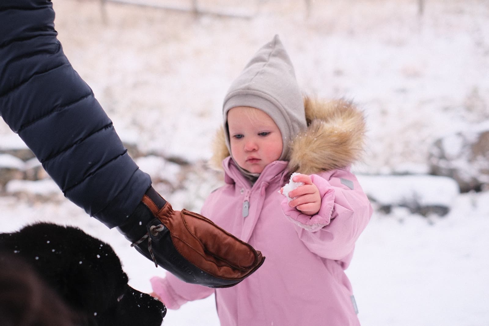 Et barn i rosa dress holder snø